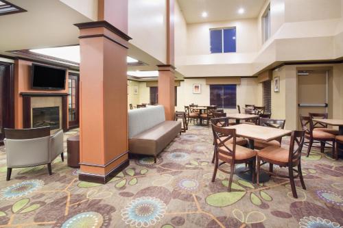 a lobby with tables and chairs and a fireplace at Holiday Inn Express Hotel & Suites Minot South by IHG in Minot