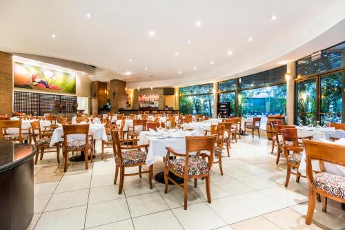 a restaurant with white tables and chairs and windows at Holiday Inn Convention Center, an IHG Hotel in Managua