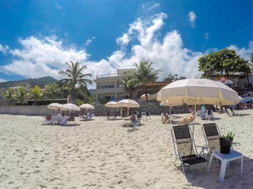 a beach with chairs and umbrellas and people on it at Juquehy La Plage Hotel in Juquei