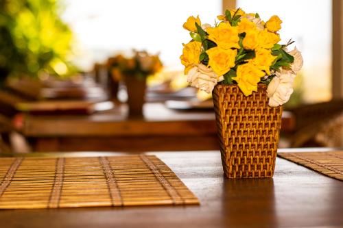 a vase of yellow flowers sitting on a table at Juquehy La Plage Hotel in Juquei