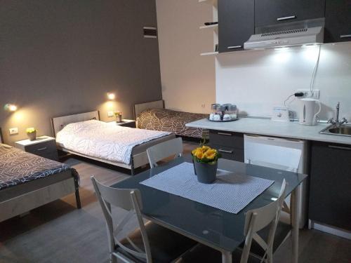 a room with two beds and a table and a kitchen at Apartman Stari most - Old Bridge in Bečej
