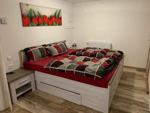 a bedroom with a bed with a red comforter at Apartmán 206 Špičák in Železná Ruda