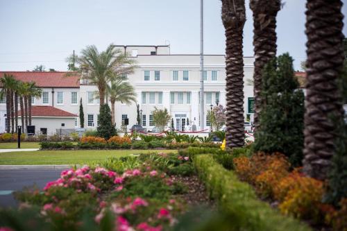 a large white building with palm trees and flowers at Centennial Plaza Resort Gulfport in Gulfport