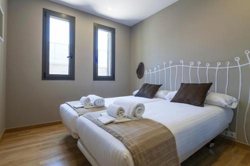 a bedroom with a large white bed with two windows at Hotel Acta Laumon in Barcelona