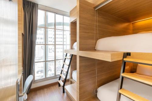 a small bedroom with a bunk bed and a window at Atnest Hostel in Bangkok