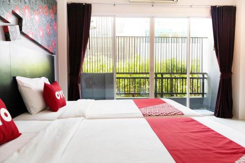 a bedroom with a large bed with red pillows and a window at OYO 792 Omsaga Phuket Hotel in Phuket