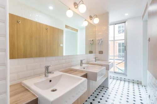 a bathroom with two sinks and a mirror at Atnest Hostel in Bangkok