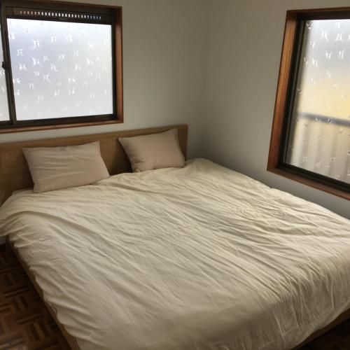 Bett in einem Zimmer mit 2 Fenstern in der Unterkunft Villa Hineno / Vacation STAY 79056 in Izumi-Sano