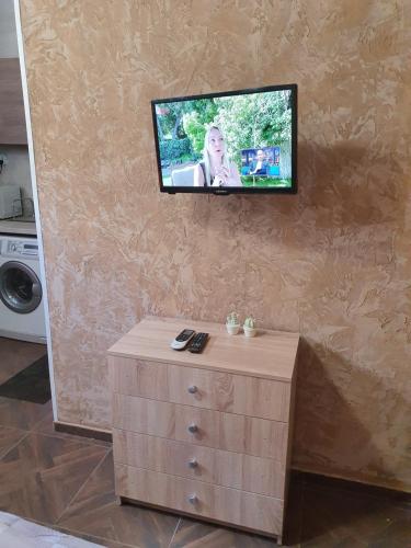 a flat screen tv on a wall with a dresser at Студио Теа in Sliven