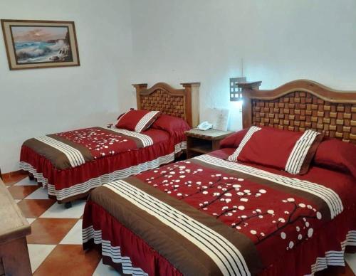 a bedroom with two beds with red comforters at Hotel Imperial Jojutla in Jojutla de Ju&aacute;rez