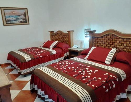 a bedroom with two beds with red comforters at Hotel Imperial Jojutla in Jojutla de Juárez
