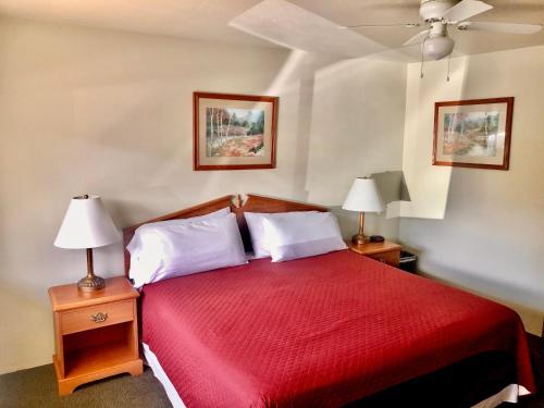 a bedroom with a large red bed with two lamps at Hiouchi Motel in Crescent City