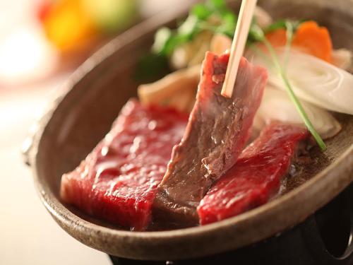 a bowl of meat and vegetables with chopsticks in it at Ryokan Biyunoyado in Yamanouchi
