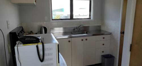 a small kitchen with a sink and a refrigerator at Cypress Court Motel in Whangarei