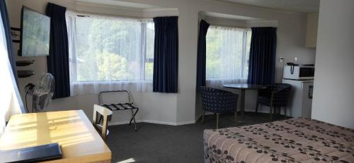 a hotel room with a bed and a table and window at Cypress Court Motel in Whangarei