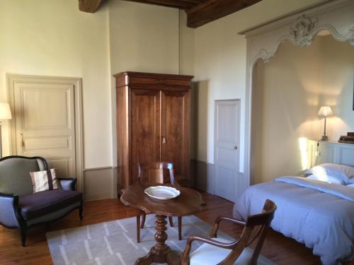 a bedroom with a bed and a table and a chair at Demeure Bouquet in Ambierle