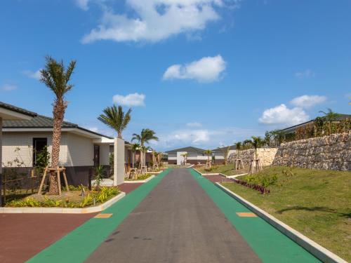 a road leading to a house with palm trees at Miyakojima Kurima Resort Seawood Hotel in Miyako Island