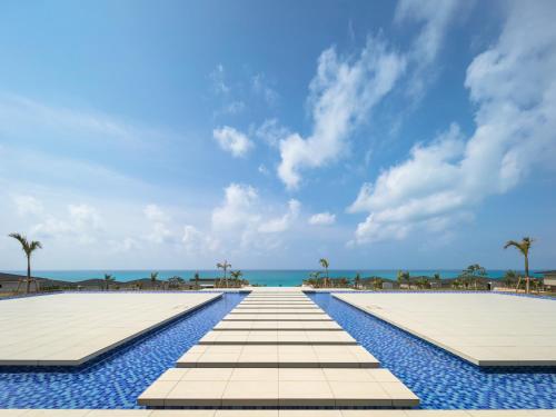 a swimming pool with the ocean in the background at Miyakojima Kurima Resort Seawood Hotel in Miyako Island