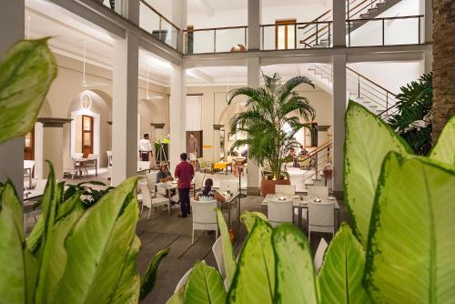 um lobby com pessoas sentadas em mesas e plantas em Villa Shanti - Heritage Hotel for Foodies em Pondicherry