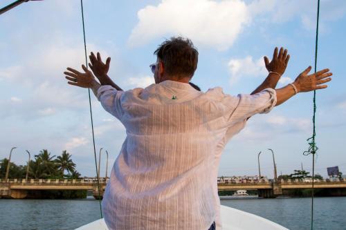 a man on a boat with his hands in the air at The Pleasure Kosgoda in Bentota