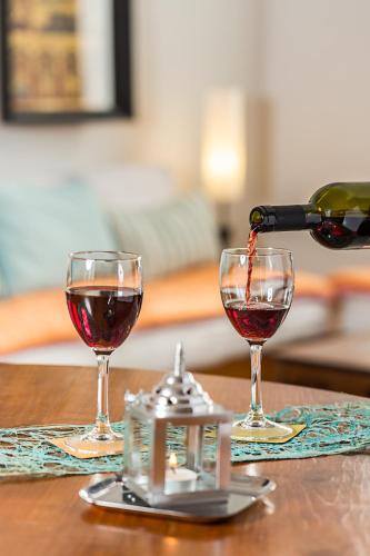 a person pouring wine into two glasses on a table at Villa Shanti - Heritage Hotel for Foodies in Puducherry