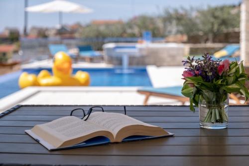 an open book on a table with a vase of flowers at Villa Blue Sky in Bol