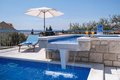 a swimming pool with an umbrella and a chair and an umbrella at Villa Blue Sky in Bol