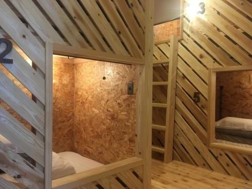 a wooden room with a shower with a ladder at Shioya Hostel in Akune
