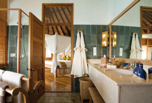 ein Bad mit einem Waschbecken und ein Bett in einem Zimmer in der Unterkunft Coco Palm Dhuni Kolhu in Thulhaadhoo