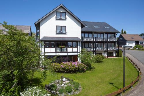 uma grande casa branca e preta com um quintal em Hotel Haus Andrea em Winterberg