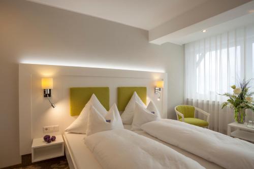 a bedroom with a large white bed with white pillows at Hotel Haus Andrea in Winterberg