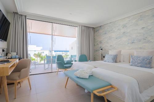 a bedroom with a large bed and a desk and chairs at Hotel Lava Beach in Puerto del Carmen