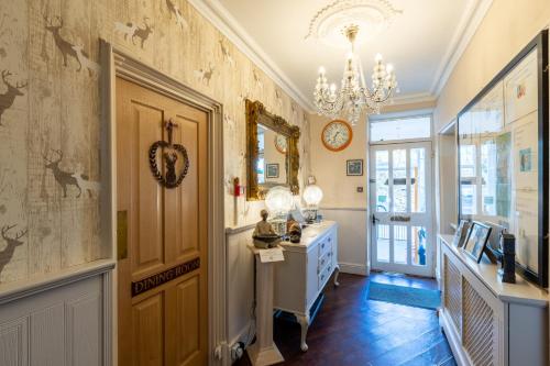 a hallway with a door and a chandelier at Holly Lodge Guest House with FREE off site health club in Windermere