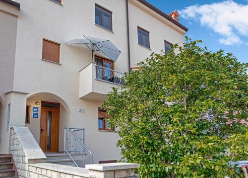 a white building with a tree in front of it at Guesthouse Residence Major in Rovinj