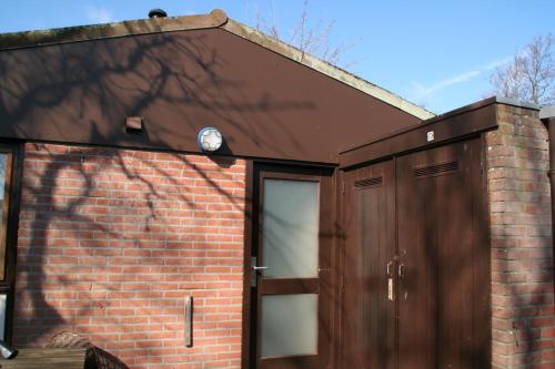 a brick house with a door and a brick wall at Rekerlanden 173 in Schoorldam