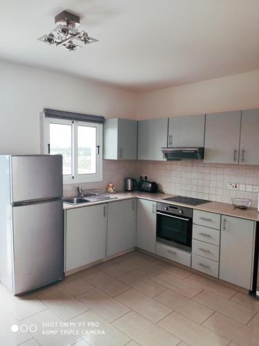 a kitchen with white cabinets and a refrigerator at Lovely holiday home,Kapparis,2 swimming pools,Wifi in Paralimni