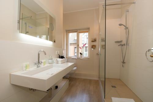 Carlstadt Suites Düsseldorf في دوسلدورف: حمام أبيض مع حوض ودش