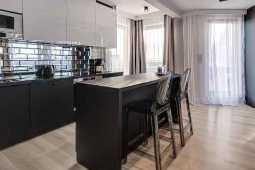 a kitchen with a black island and two chairs at Apartamenty Rondo in Świnoujście