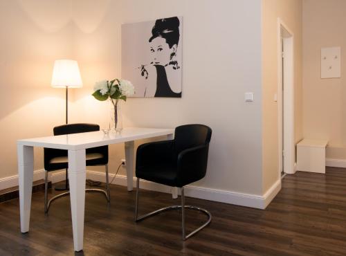 a white table with two chairs and a vase of flowers at Living am Carlsplatz Apartment in Düsseldorf