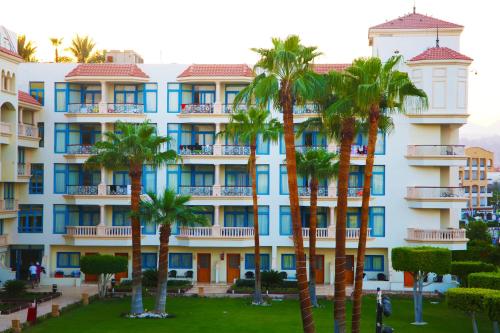 a building with palm trees in front of it at Marina Sharm Hotel in Sharm El Sheikh