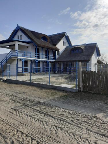 a house on the beach next to a fence at Pensiunea Stuf-Est in Sfântu Gheorghe