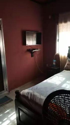 a bedroom with a red wall with a bed and a window at HAKABA in Conakry