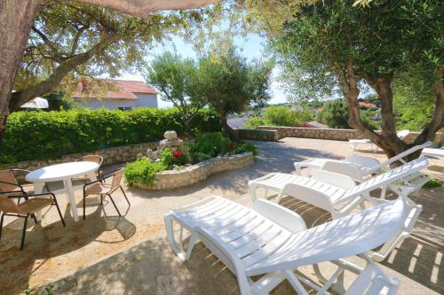 a group of white chairs and tables and trees at Apartments Delminium in Lun