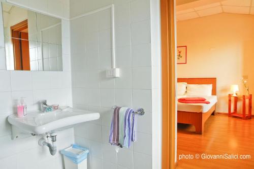 a bathroom with a sink and a bedroom at Lake Como Peace Lodge - Casa della Pace in Menaggio