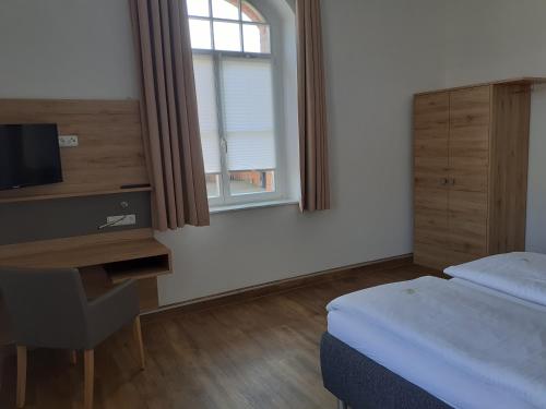 Dormitorio con cama, escritorio y TV en Ferienwohnung Diana, en Wilhelmshaven
