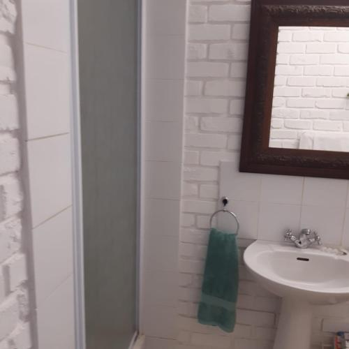 a white bathroom with a sink and a mirror at De Heide Guesthouse in Bothaville