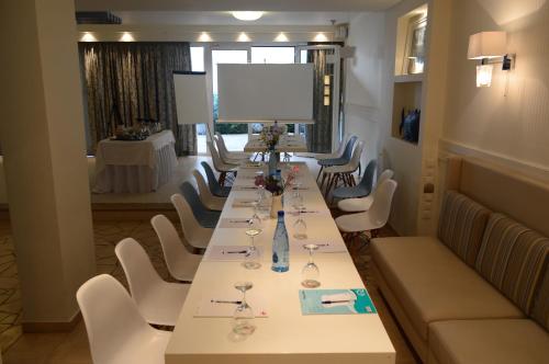 a conference room with a long table and white chairs at Oasis Beach Hotel in Skala
