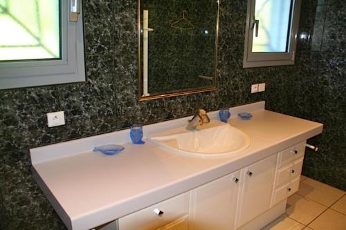 une salle de bain avec un lavabo et un miroir dans l'établissement Beautiful flowery garden, pool and pleasant house, à Lacanau