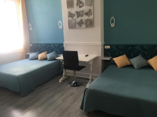 a room with two beds and a desk with a computer at Hotel Au Chapon Fin in Poitiers