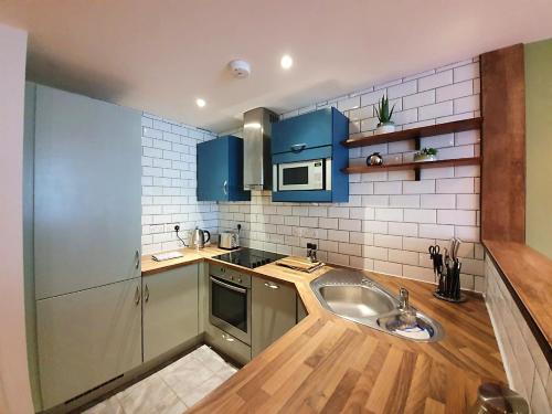 a kitchen with blue cabinets and a sink at Hotel Apartments ByDesign in Swindon